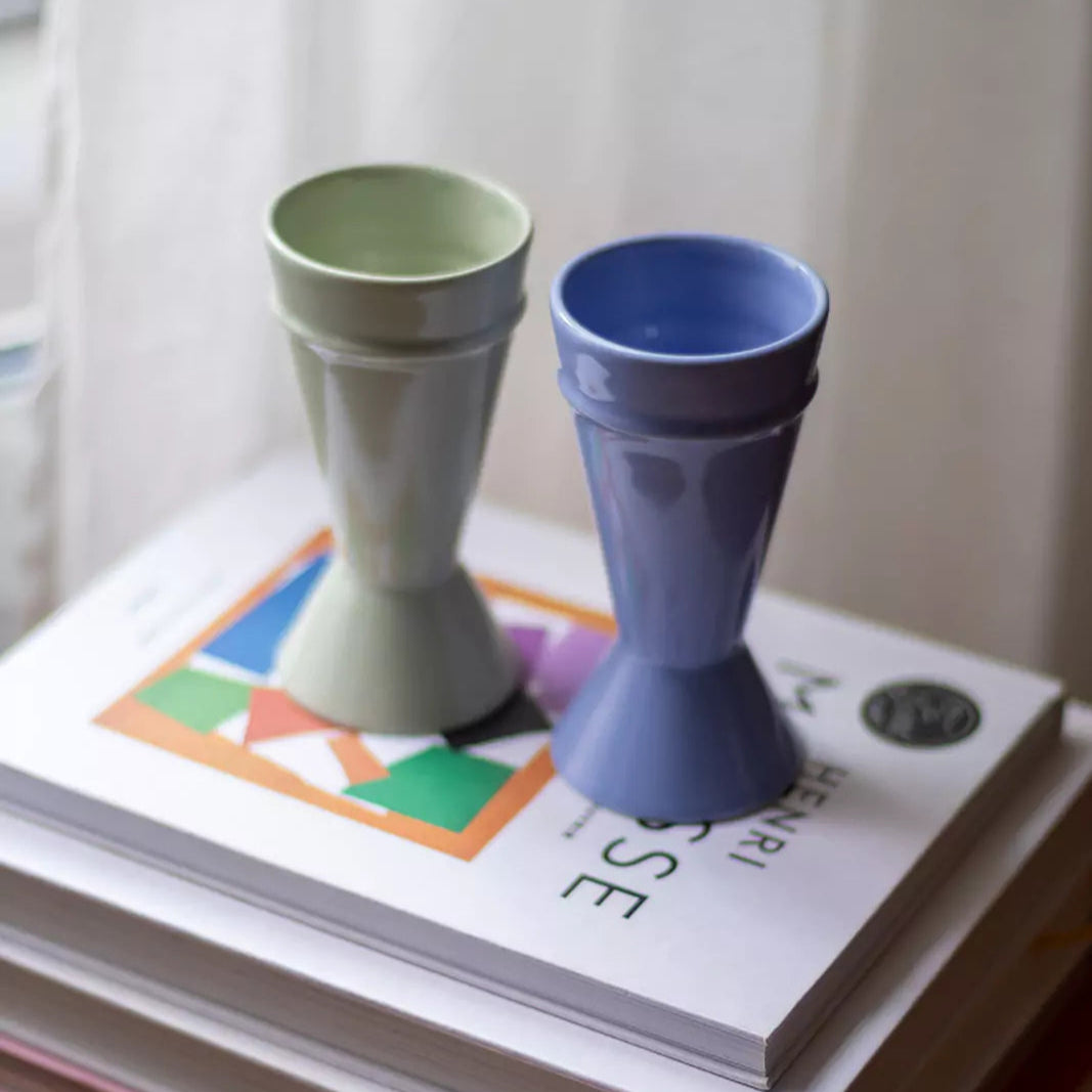 Deux tasses mazagran en céramique posées sur une pile de livres près d'une fenêtre – Atelier Maison Quatre.