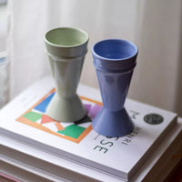 Deux tasses mazagran en céramique posées sur une pile de livres près d'une fenêtre – Atelier Maison Quatre.